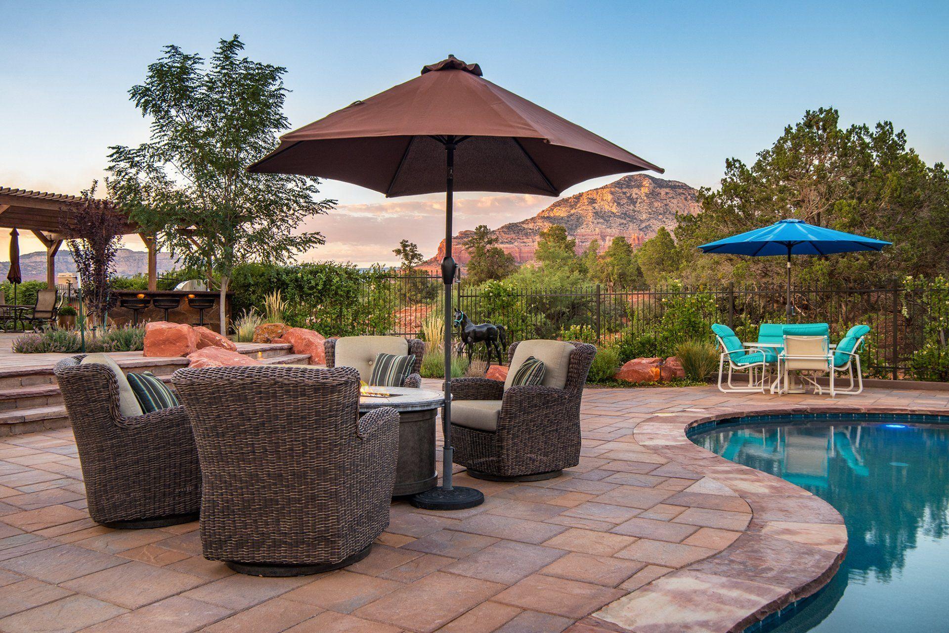 A patio with chairs and umbrellas next to a swimming pool.