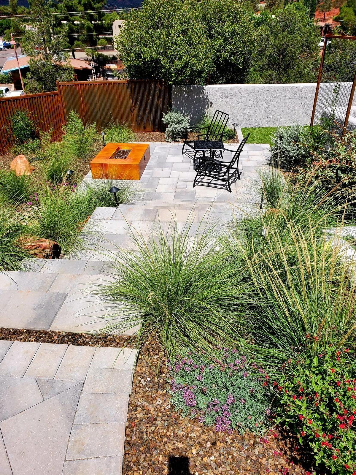 Paver patio with a corten fire pit and bistro chairs among ornamental grasses