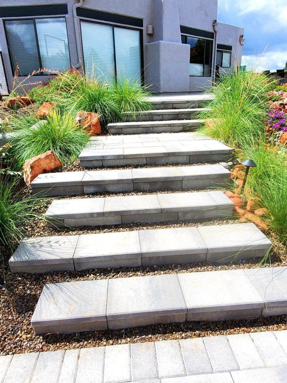 Paver steps climbing between ornamental grasses to a stucco home