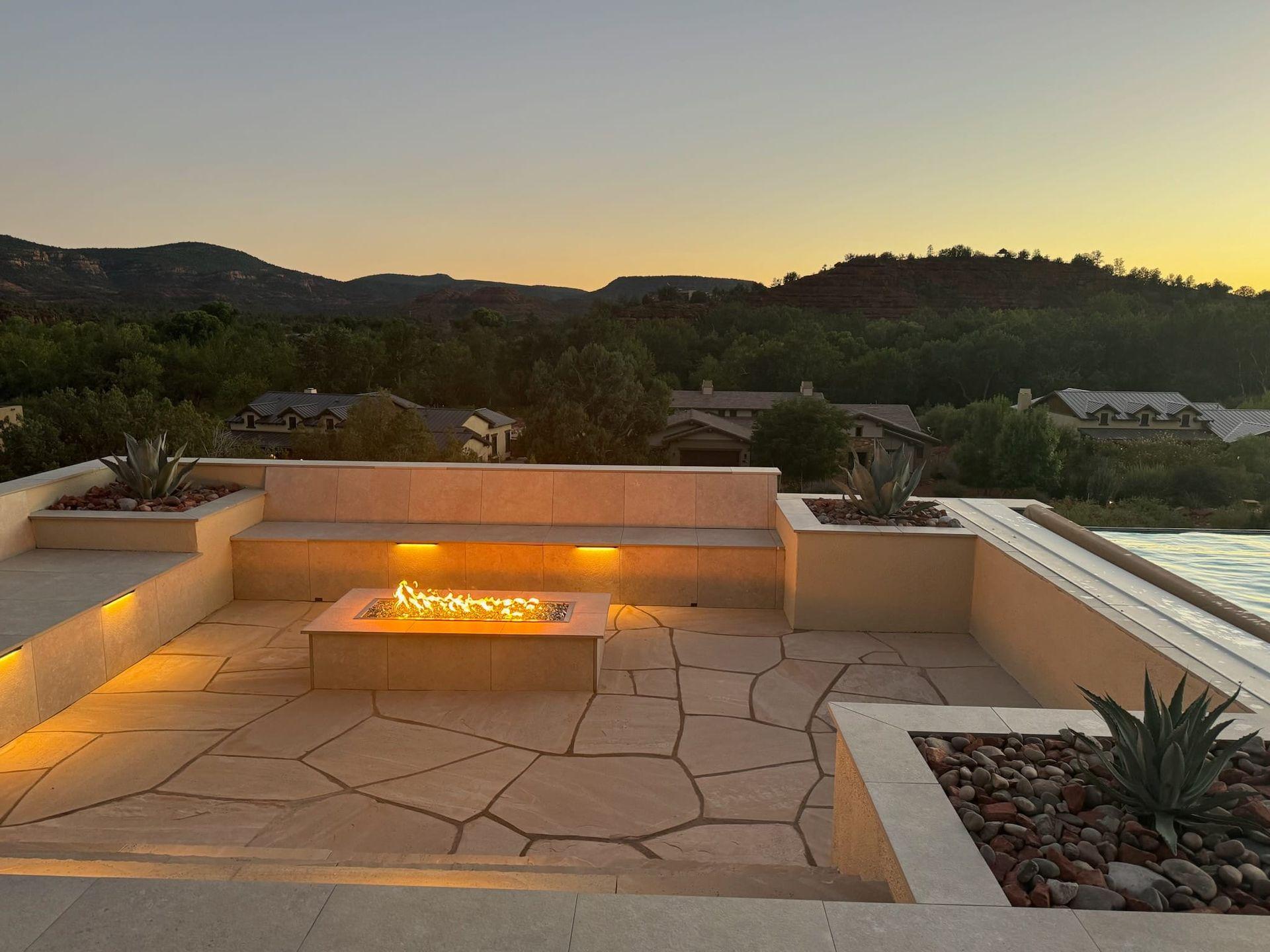 Sunken flagstone patio with a linear fire pit and built-in seating at sunset