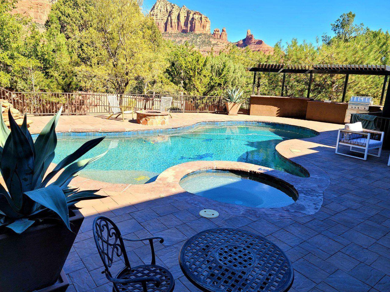 A large swimming pool with a table and chairs in front of it